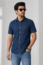 Man wearing a dark indigo short-sleeve denim shirt with light blue jeans and sunglasses.