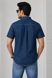 Man wearing a dark indigo short-sleeve denim shirt with light blue jeans and sunglasses.